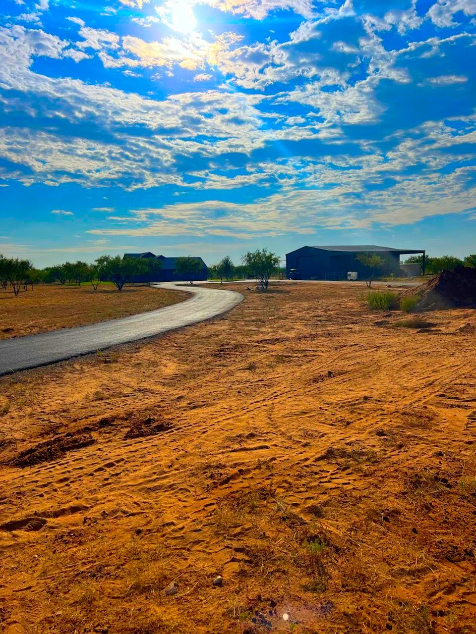 Long new asphalt driveway across a ranch property, August 2024