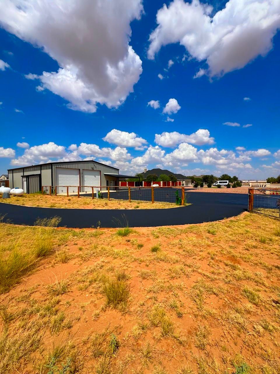 New asphalt circle drive in front of a metal shop building, August 2024
